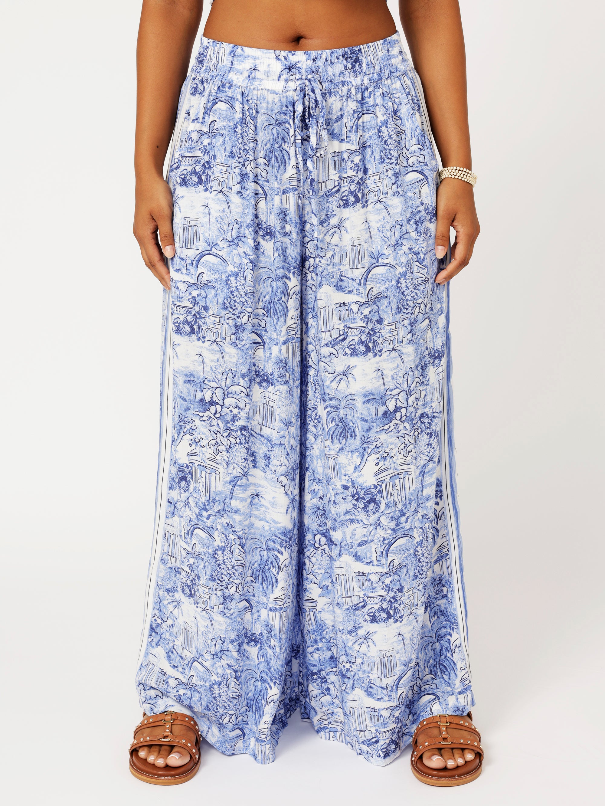 close up Front view of model wearing the Lost City Palazzo Pants in blue Toile de Jouy rayon print with contrast side stripe