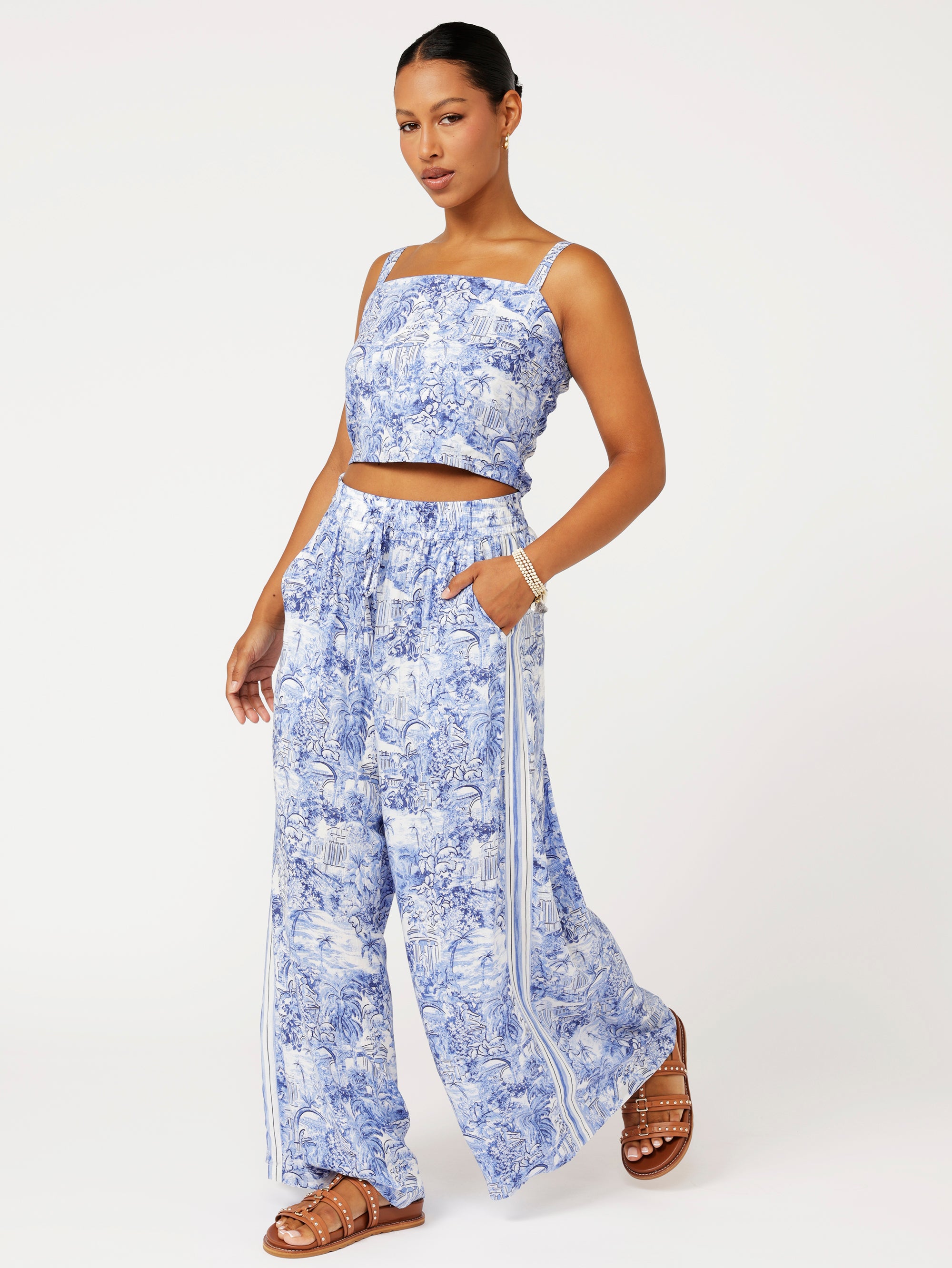 side view of model wearing the Lost City Palazzo Pants in blue Toile de Jouy rayon print with contrast side stripe