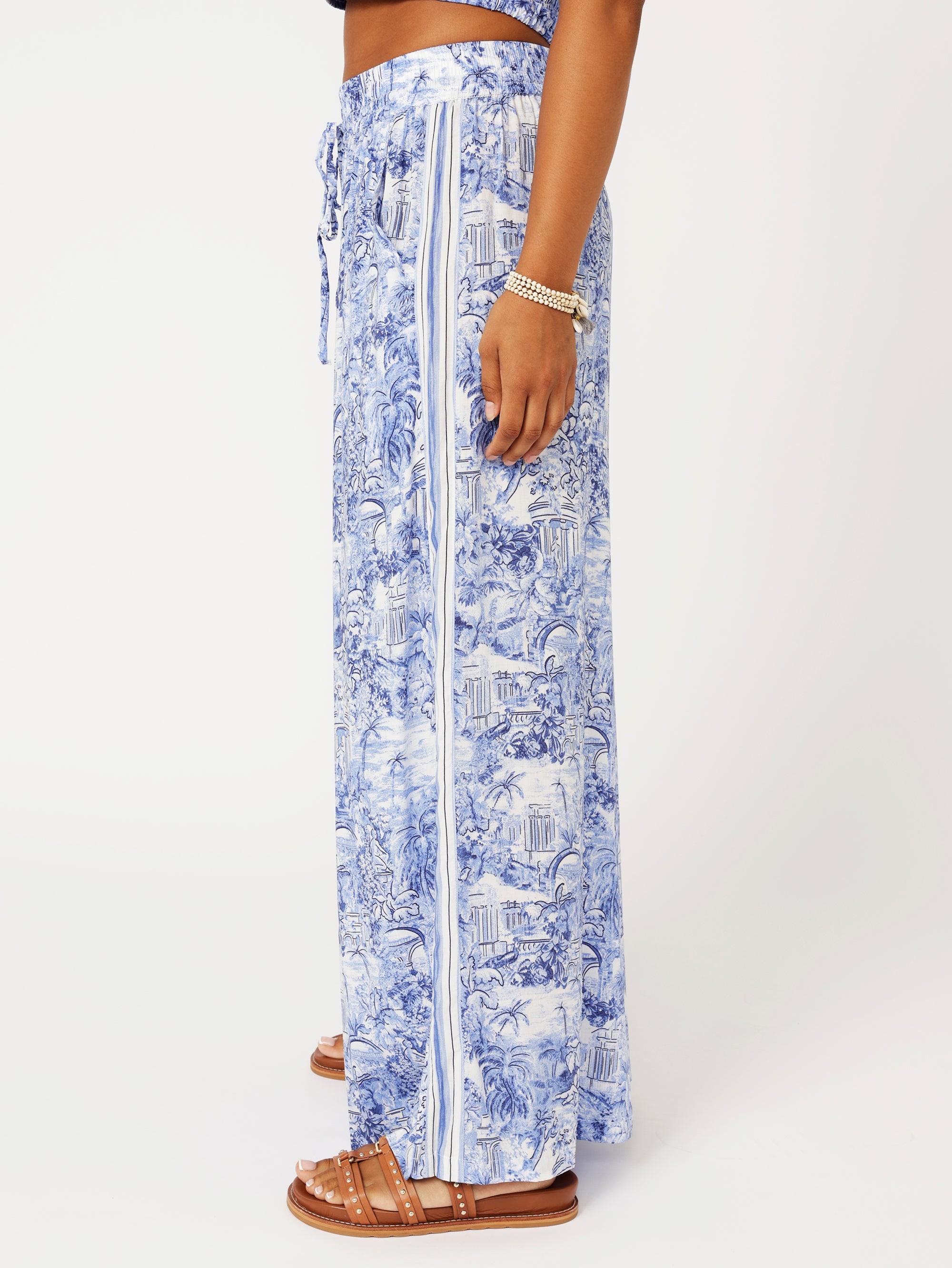 close up side view of model wearing the Lost City Palazzo Pants in blue Toile de Jouy rayon print with contrast side stripe