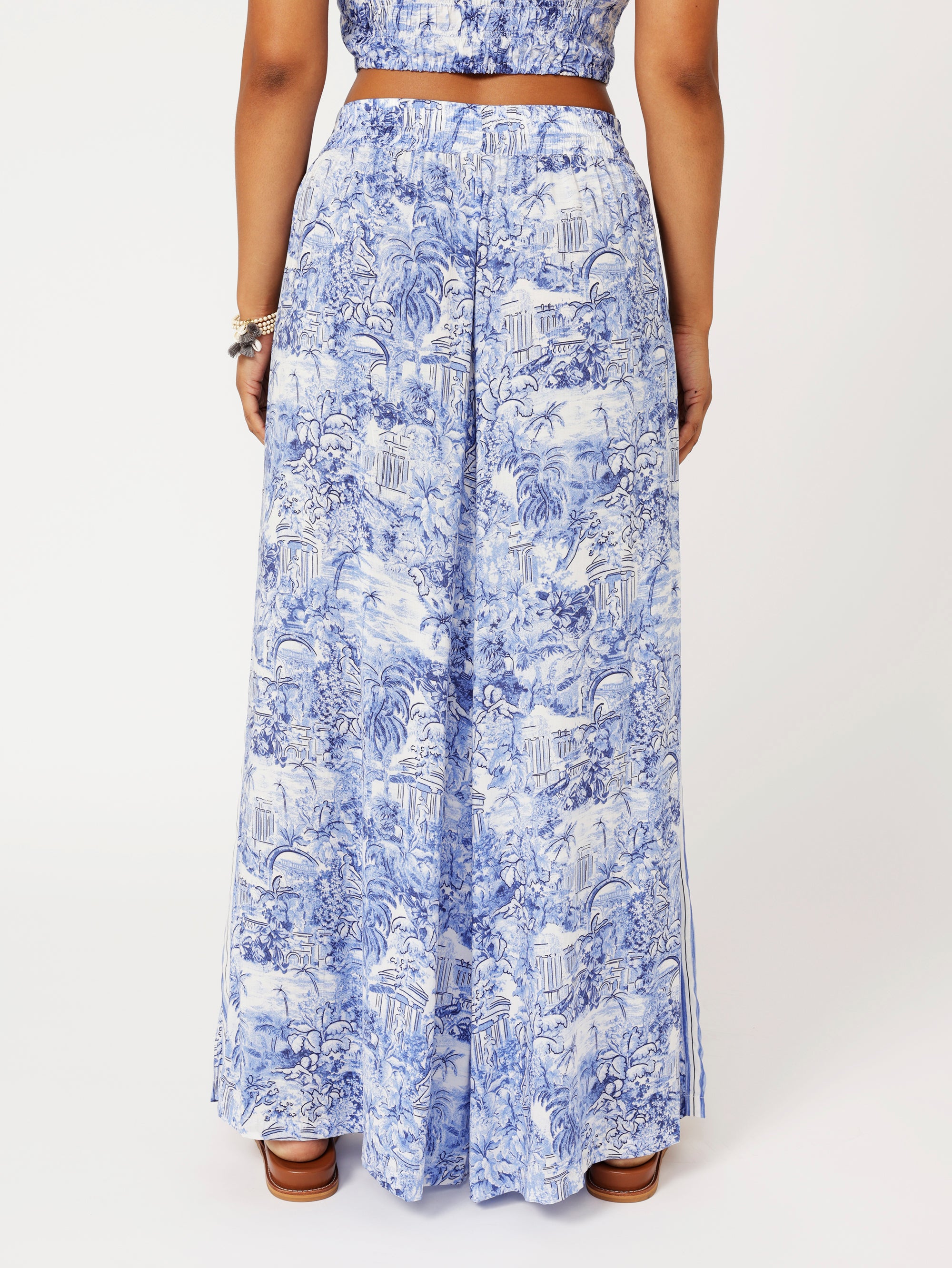 close up back view of model wearing the Lost City Palazzo Pants in blue Toile de Jouy rayon print with contrast side stripe