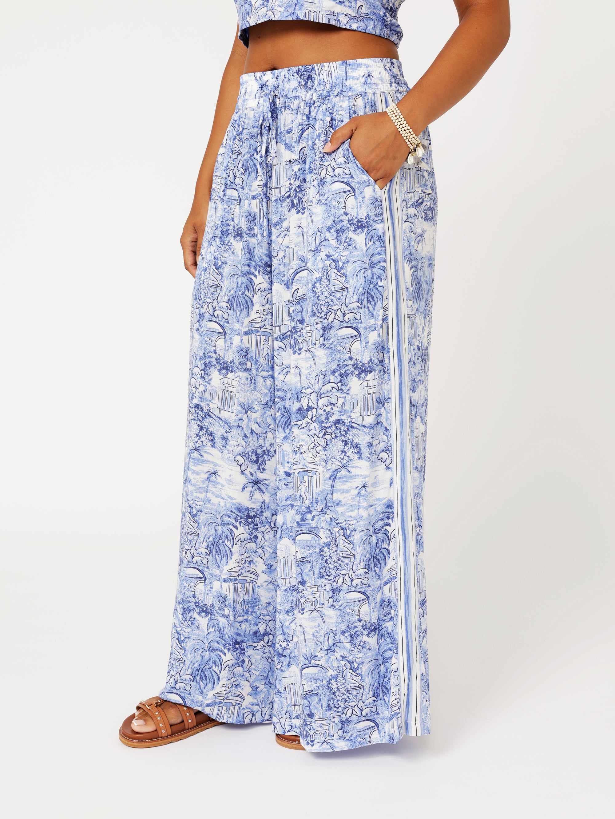 close up side view of model wearing the Lost City Palazzo Pants in blue Toile de Jouy rayon print with contrast side stripe