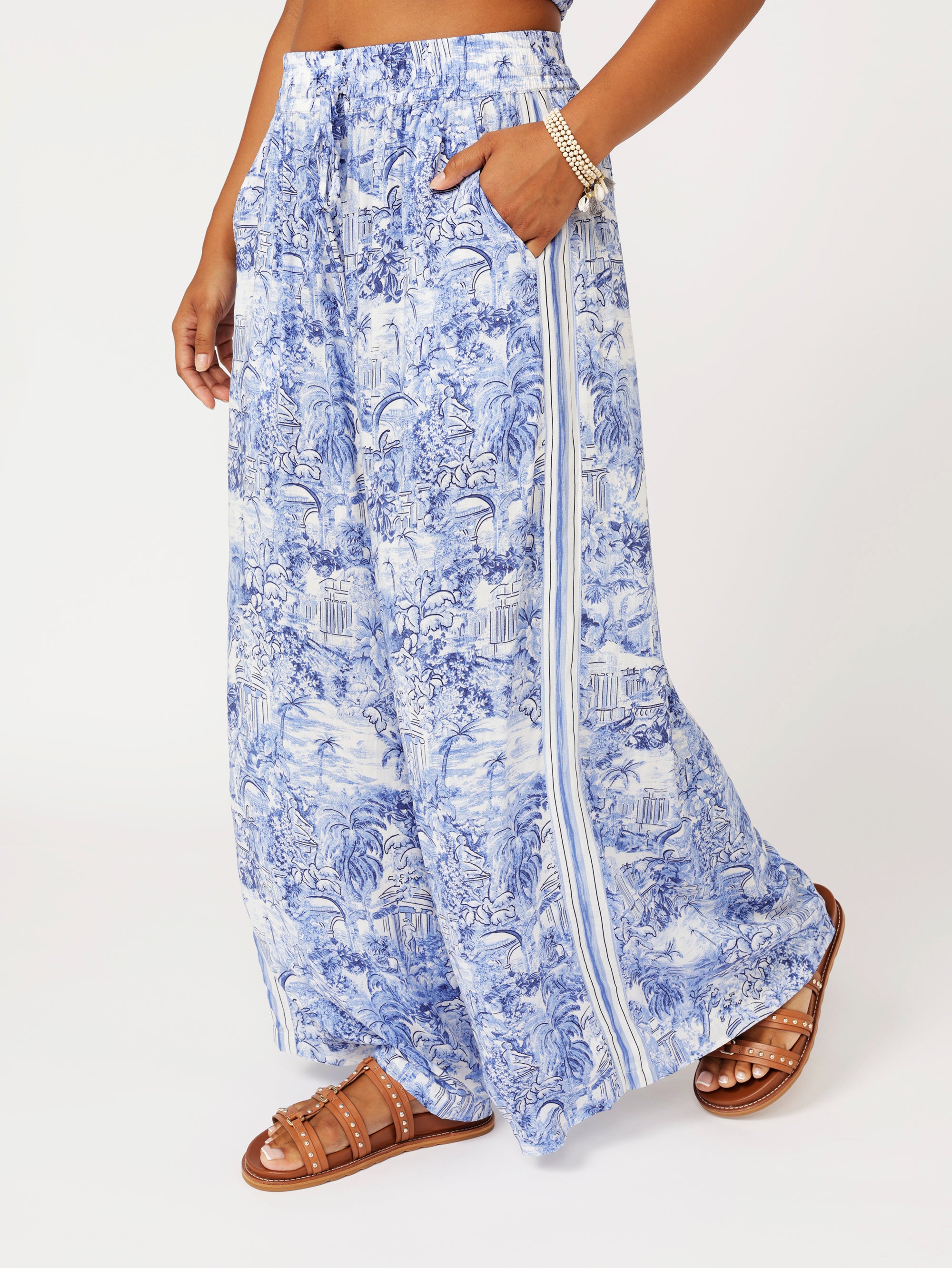 close up of model wearing the Lost City Palazzo Pants in blue Toile de Jouy rayon print with contrast side stripe