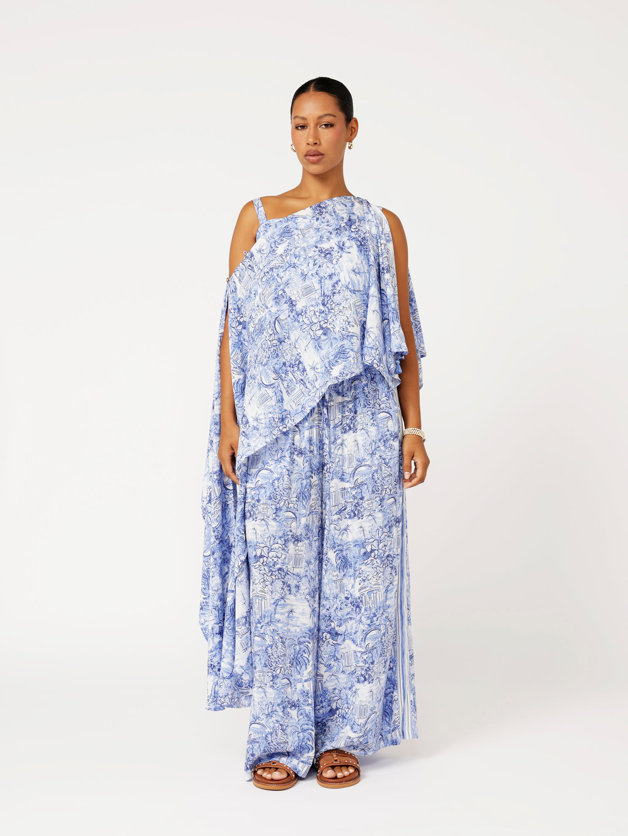Styled front view of model wearing the Lost City Palazzo Pants in blue Toile de Jouy rayon print with contrast side stripe, paired with the matching Soirée Wrap.