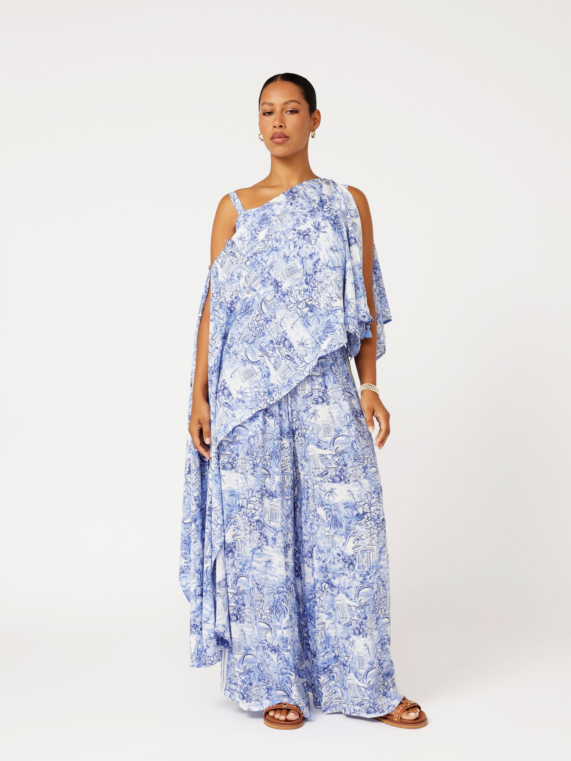 Styled front view of model wearing the Lost City Palazzo Pants in blue Toile de Jouy rayon print with contrast side stripe, paired with the matching Soirée Wrap.