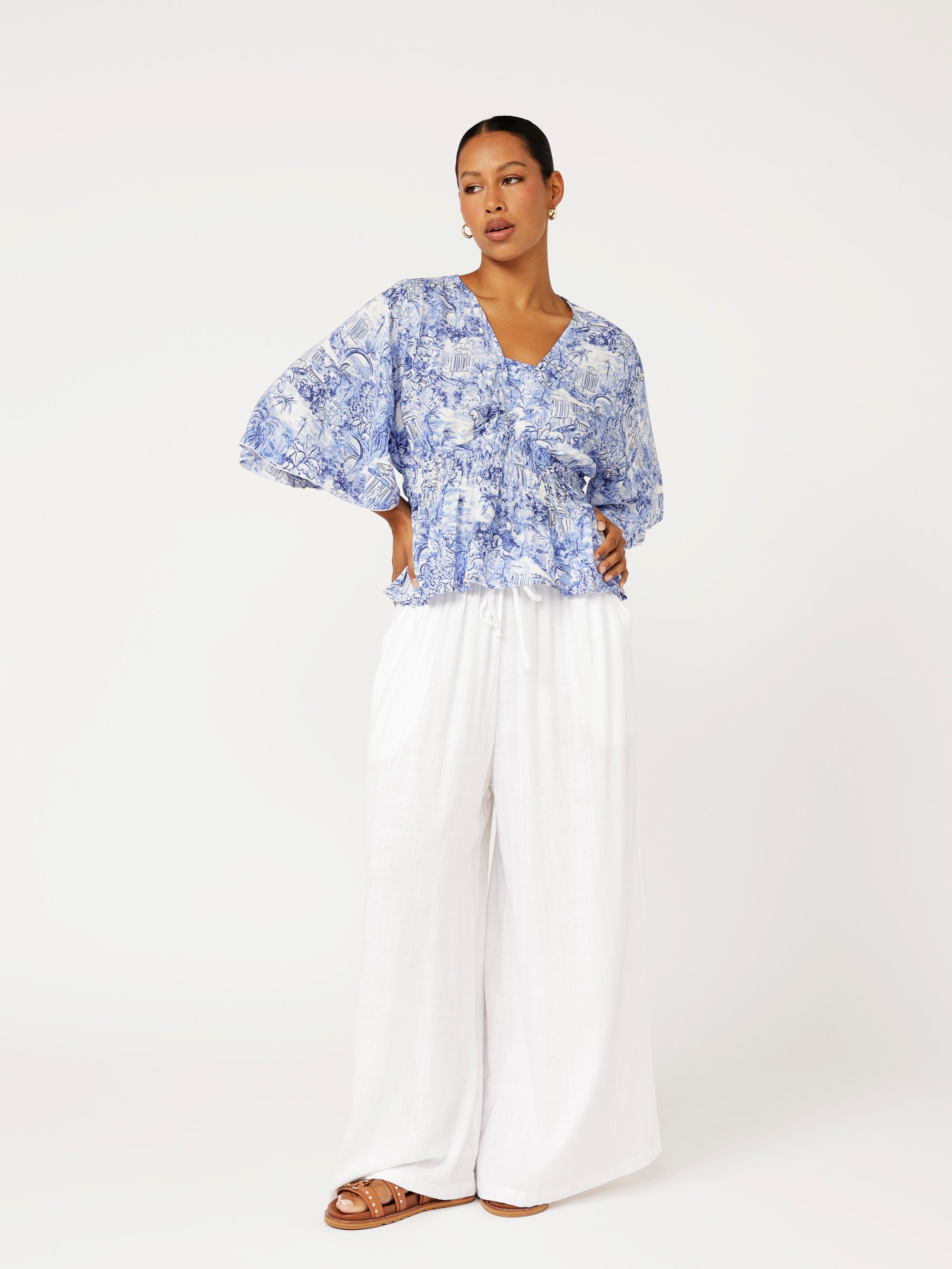Styled look featuring ruched blue Toile de Jouy top with white wide-leg palazzo pants for a fresh resort look