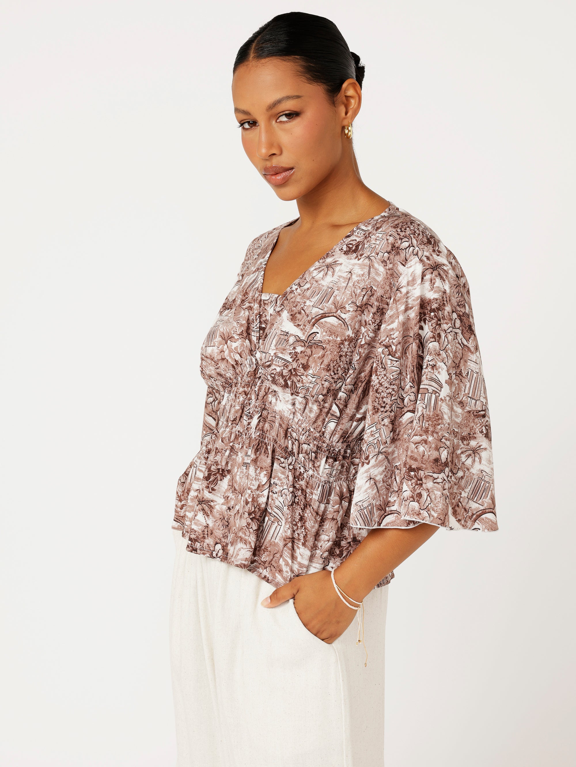 Close-up of ruched waist and Toile de Jouy print on brown rayon top