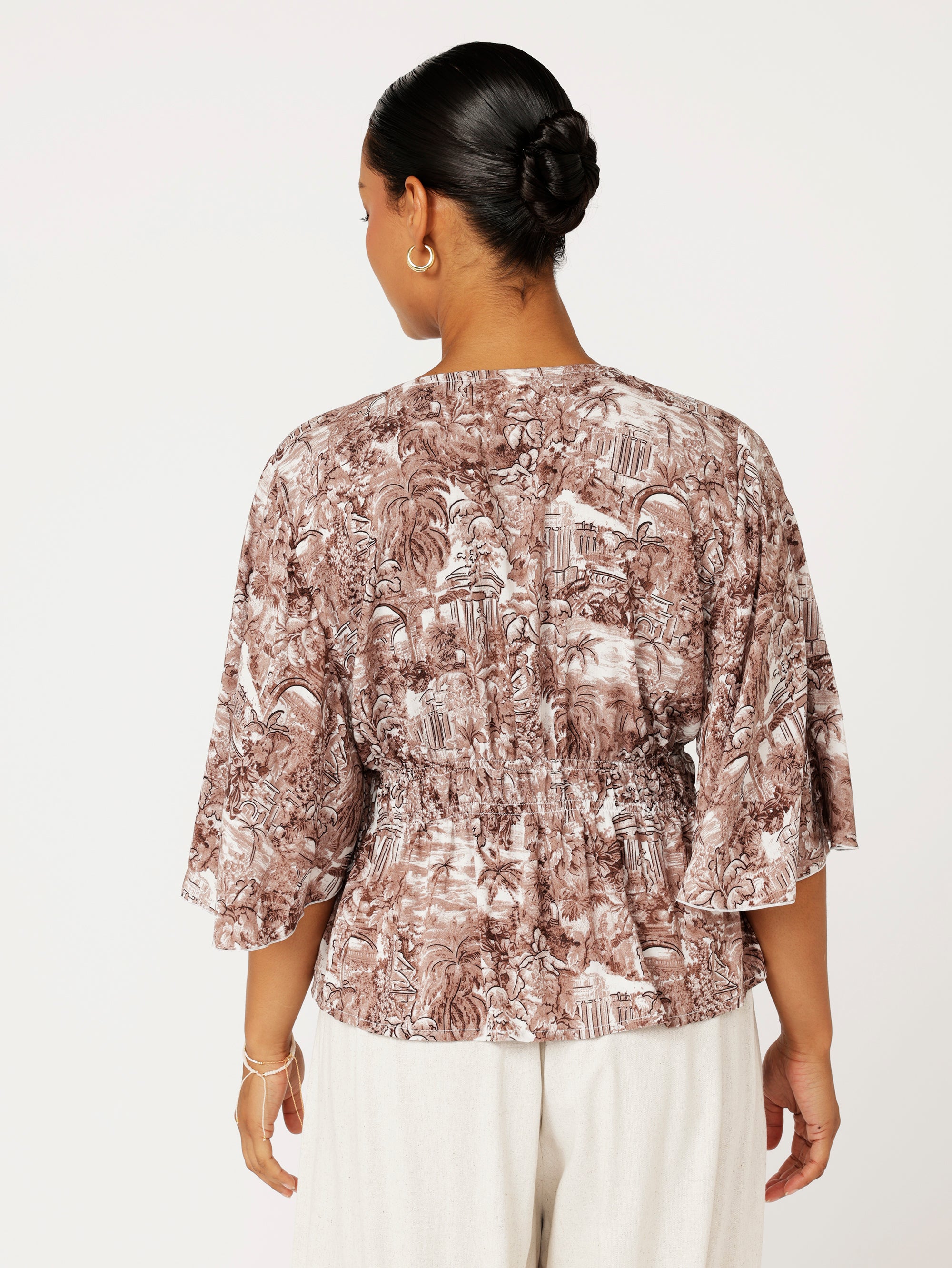 Close-up back view of ruched waist and Toile de Jouy print on brown rayon top
