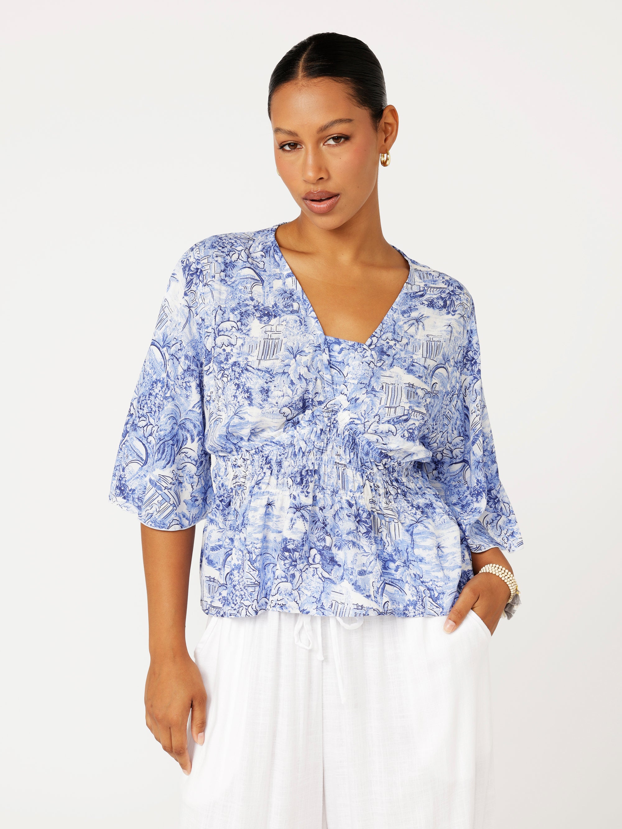 front view of model wearing a ruched blue Toile de Jouy top with fluted sleeves