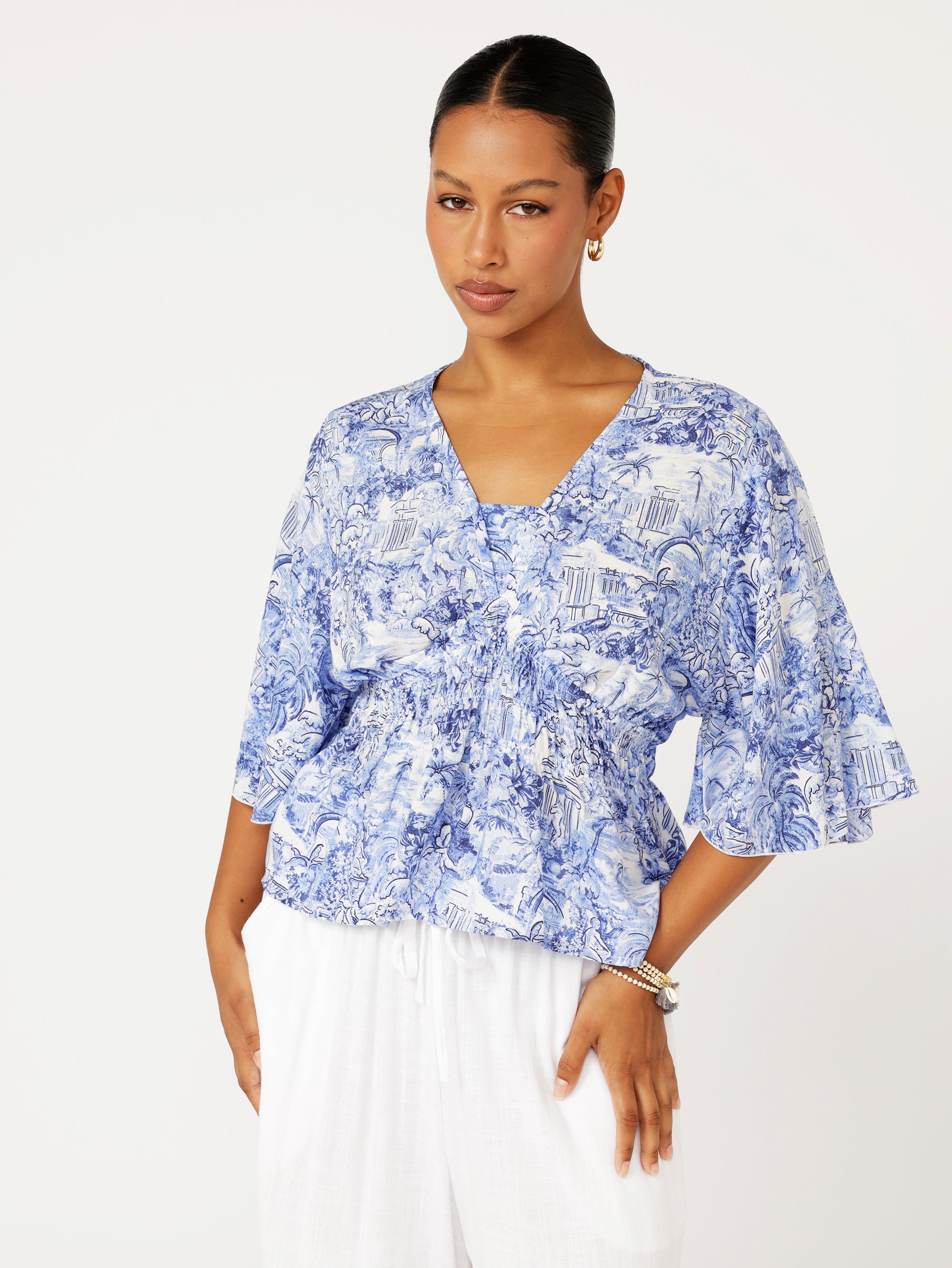 front view of model wearing a ruched blue Toile de Jouy top with fluted sleeves