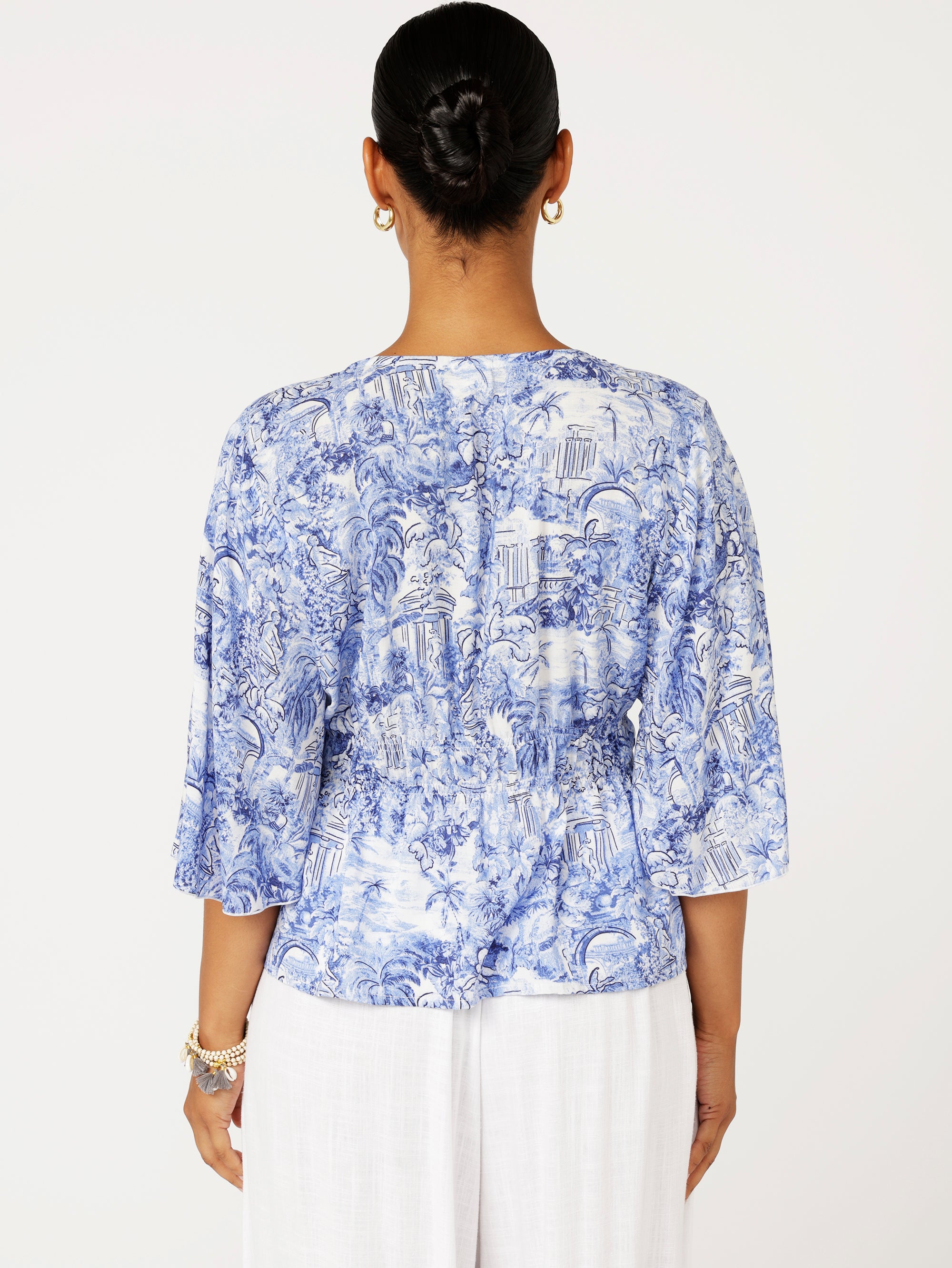back view of model wearing a ruched blue Toile de Jouy top with fluted sleeves