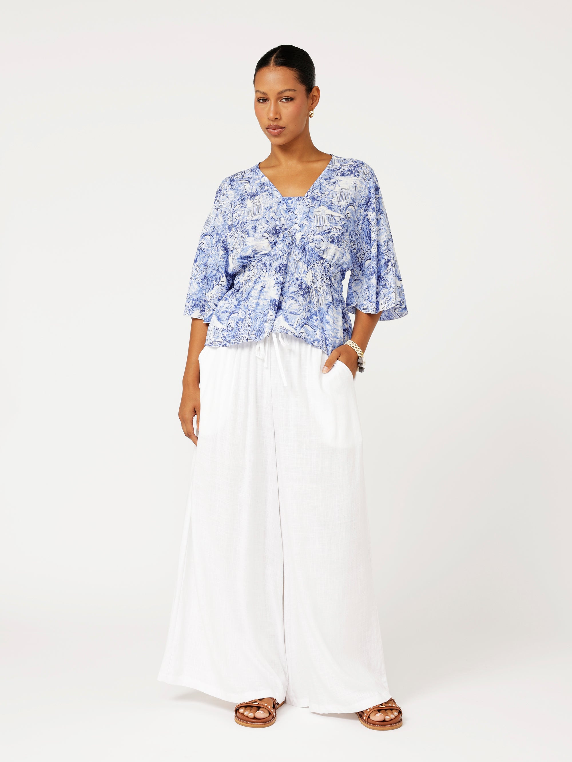 Styled look featuring ruched blue Toile de Jouy top with white wide-leg palazzo pants for a fresh resort look