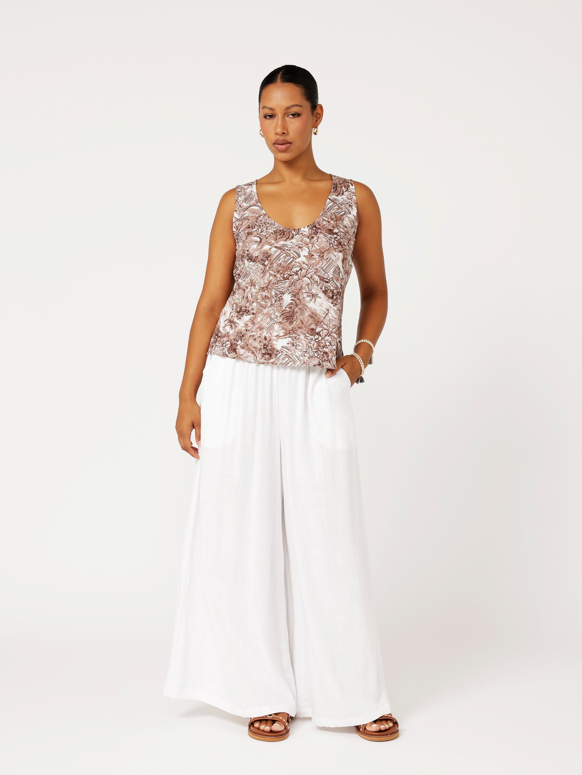 Front view of model wearing the Scoop Neck Top in brown Toile de Jouy rayon print paired with white wide-leg pants for a fresh resort look