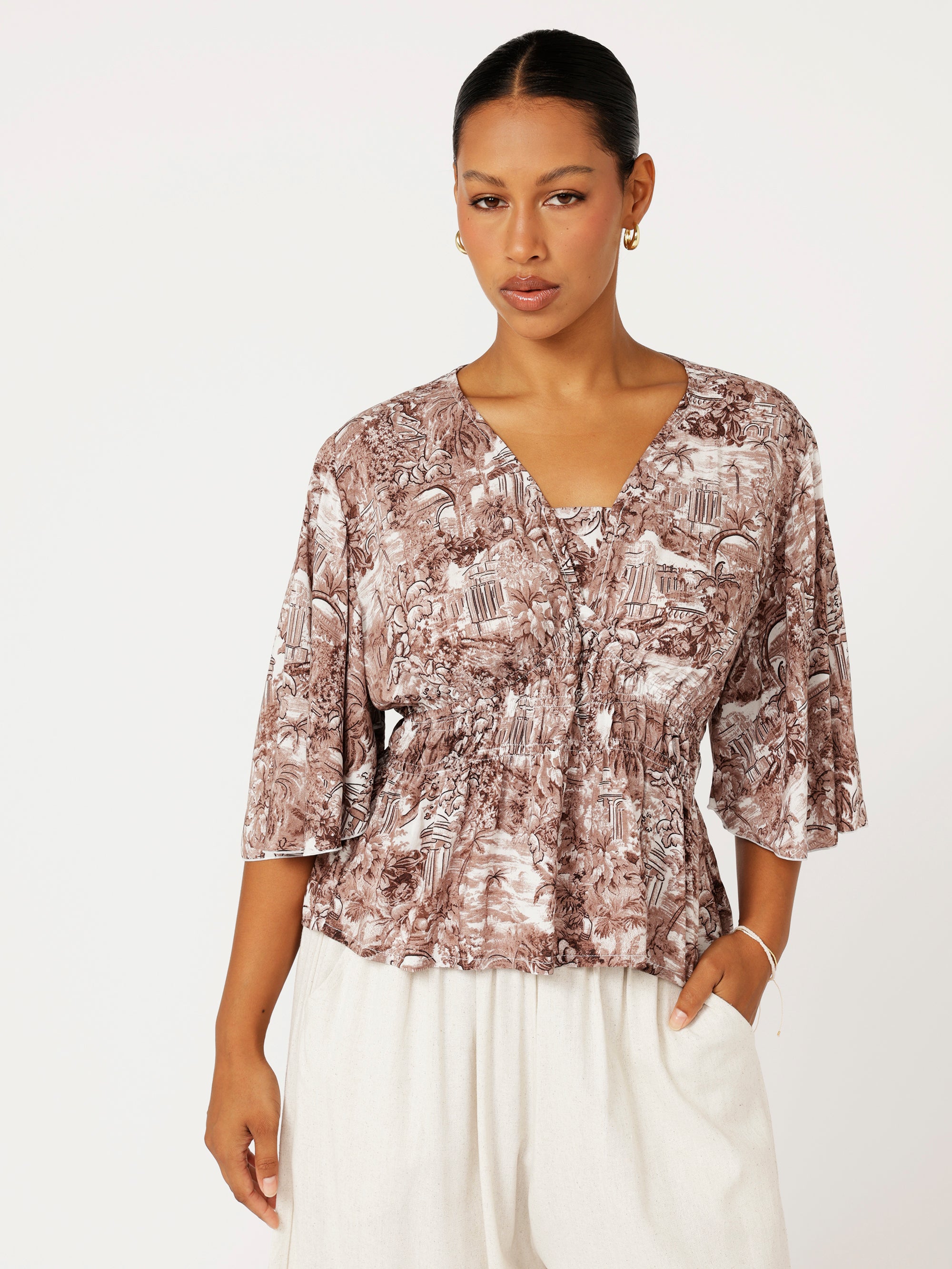 lose-up of ruched waist and Toile de Jouy print on brown rayon top