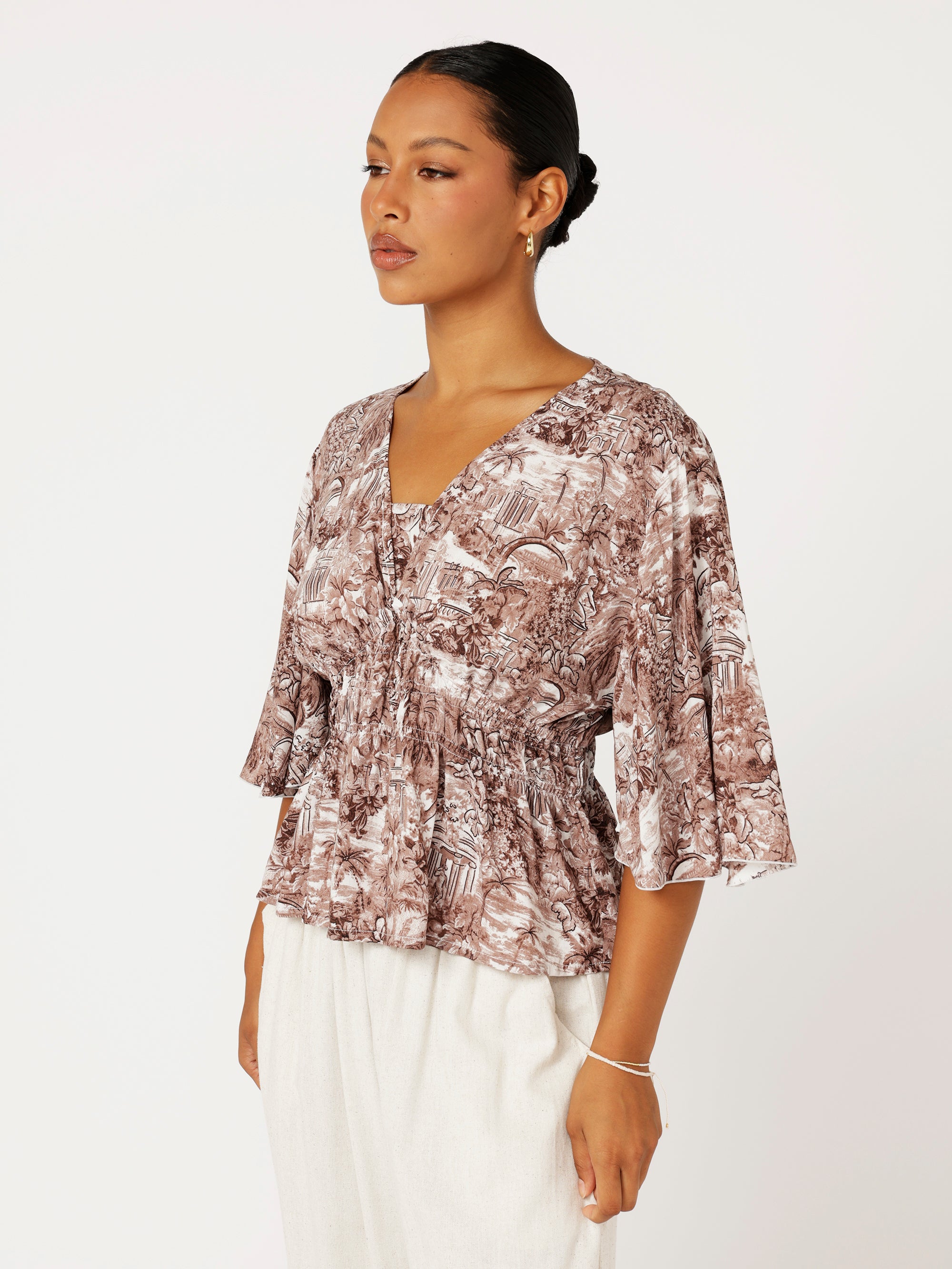 Close-up of ruched waist and Toile de Jouy print on brown rayon top