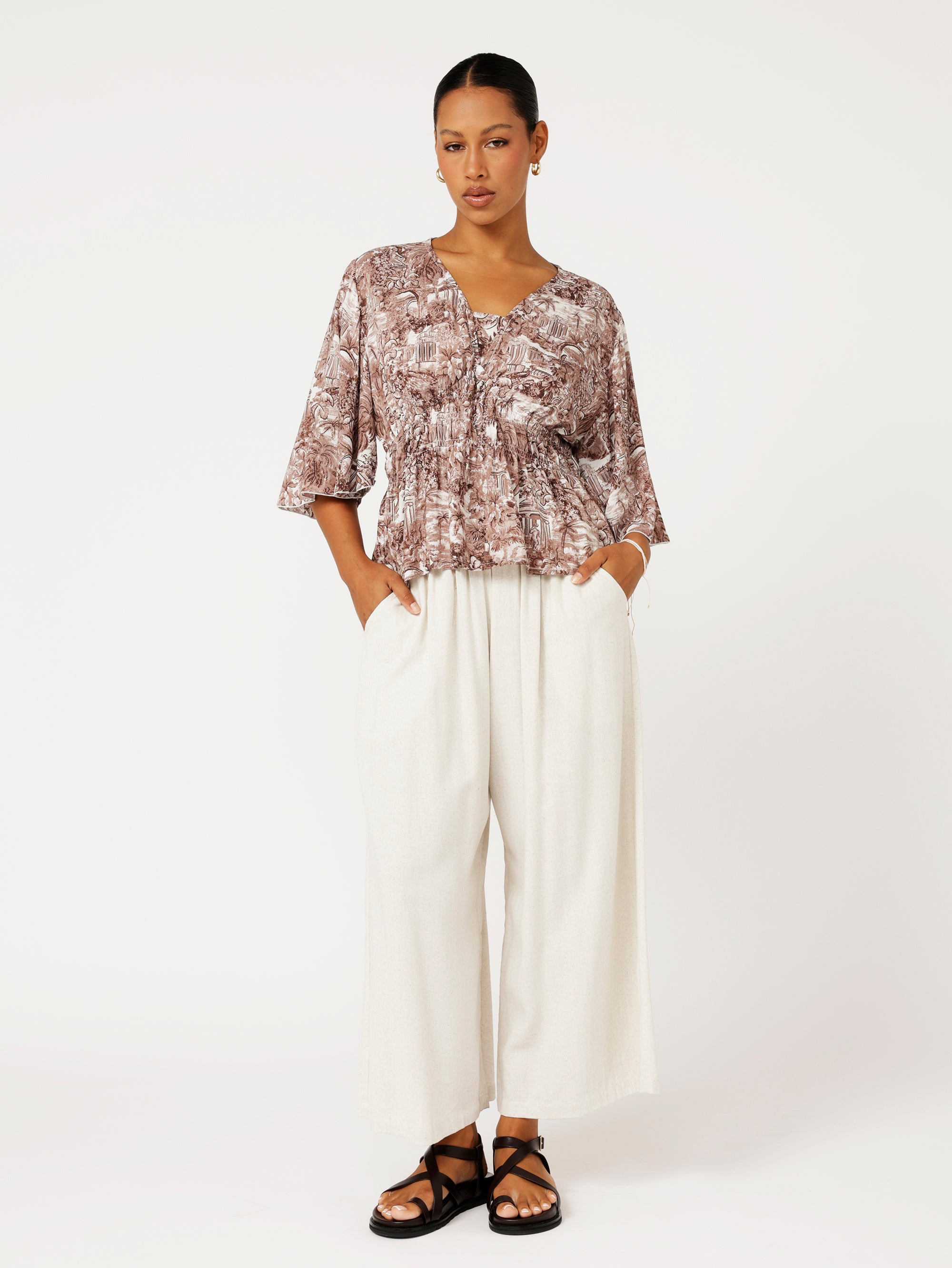 styled look of brown Toile de Jouy top with fluted sleeves and ruched waist styled with natural linen pants.